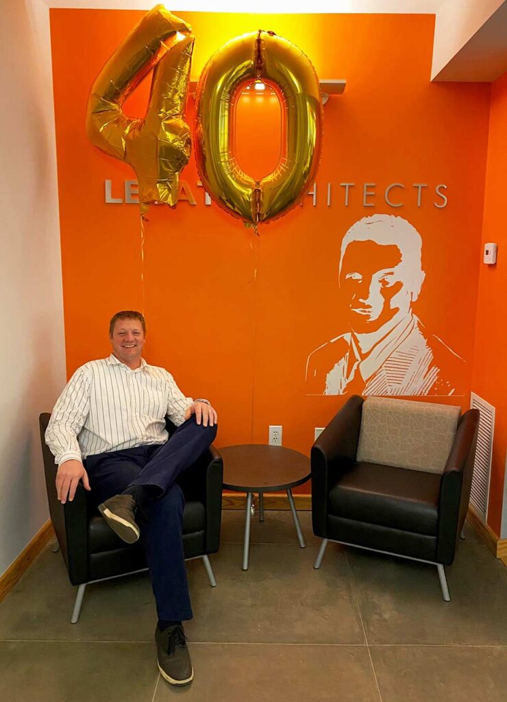 Architect sitting in lounge with orange wall and 40 balloon