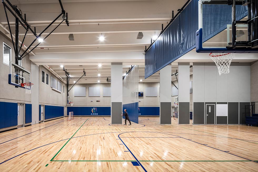 Man slides panels across gym floor.