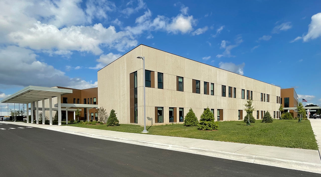 School facade with metal canopy entry and precast concrete classroom wing