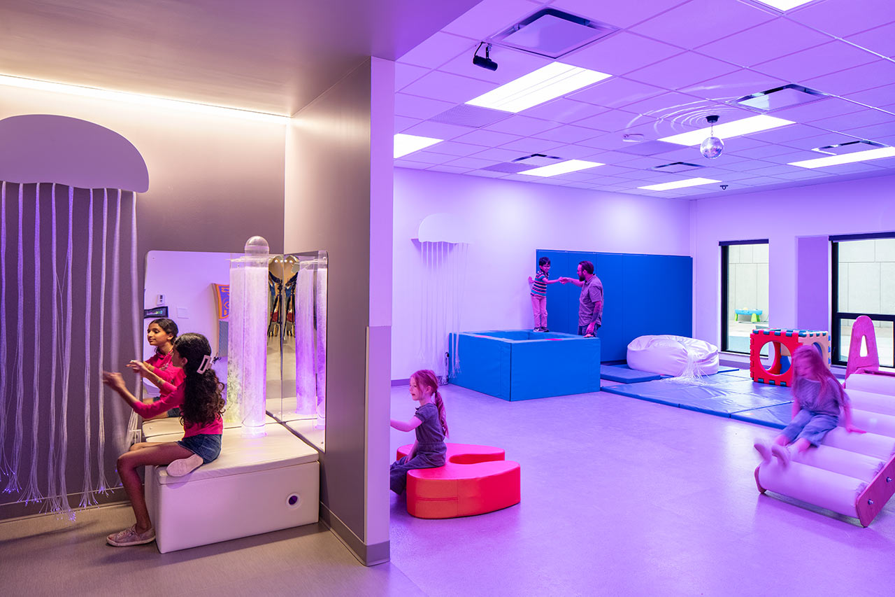 Children play in specialized therapy rooms with unique lighting.