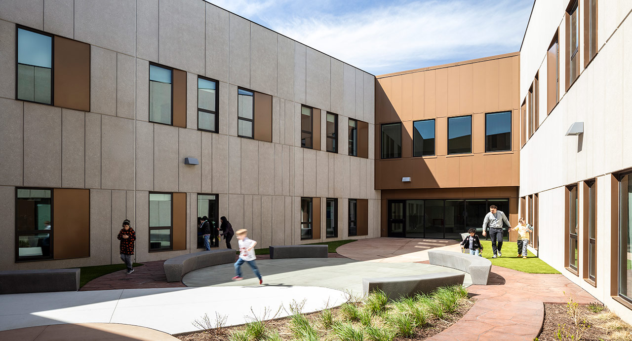 Children play in a courtyard surrounded by a school