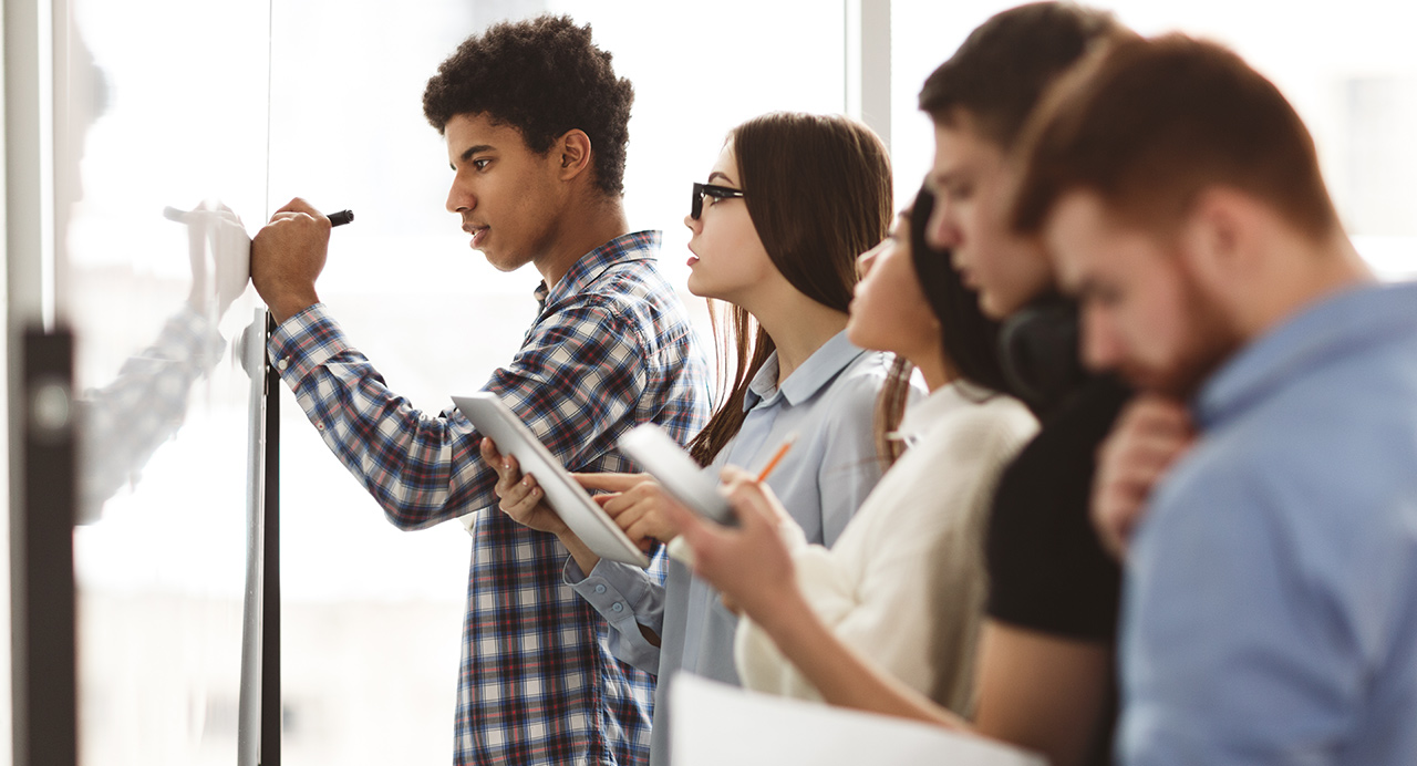 High school students work at whiteboard on assignment related to the Arc dashboard