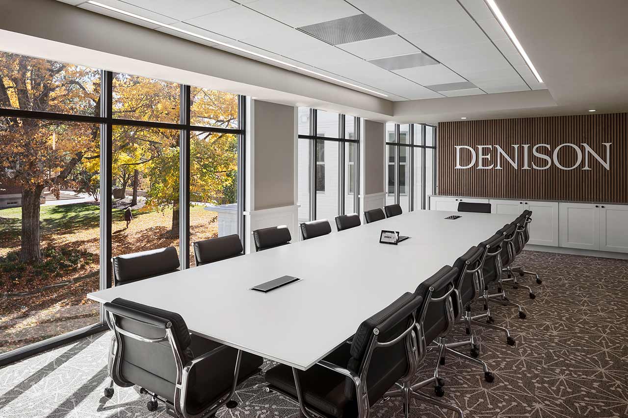 Conference room with glass table, modern chairs, view of college campus