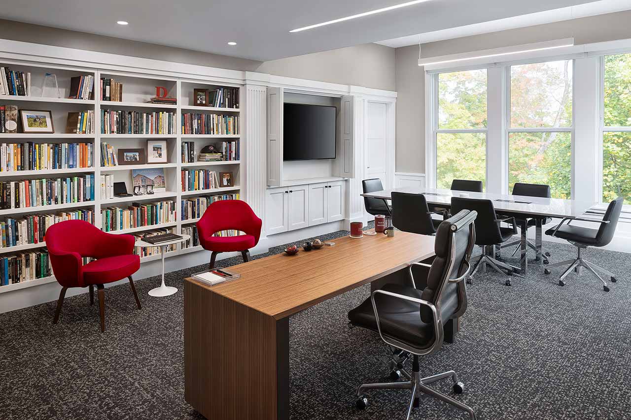 Contemporary college office with modern furniture, white bookcases, and view of campus