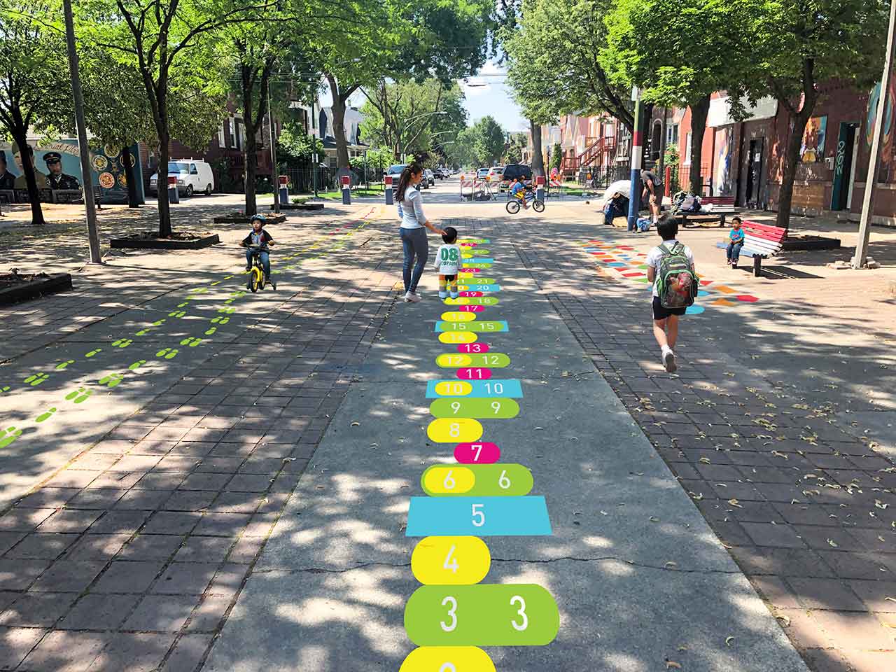 Urban setting with children playing math game installed on sidewalk